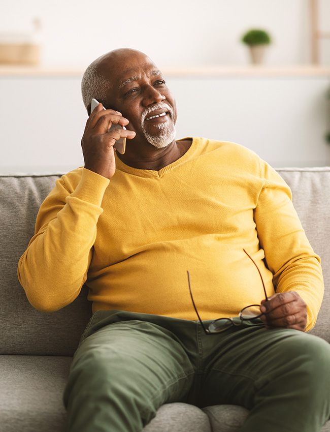 man-relaxing-on-couch-on-phone African american man relaxing on the couch chatting on his phone